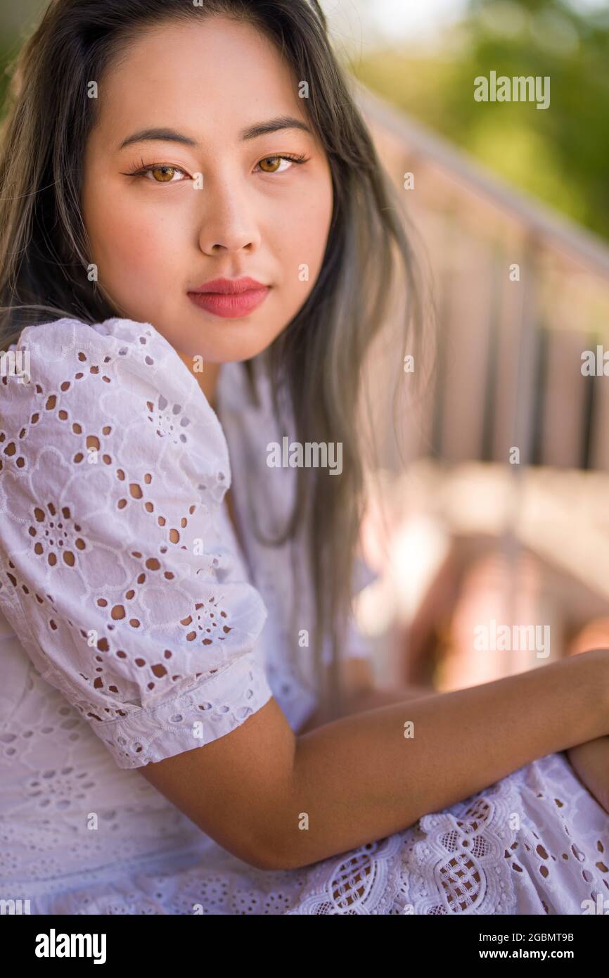 Portrait of a Young Asian Woman in a White Summer Dress Seated on Staircase Stock Photo