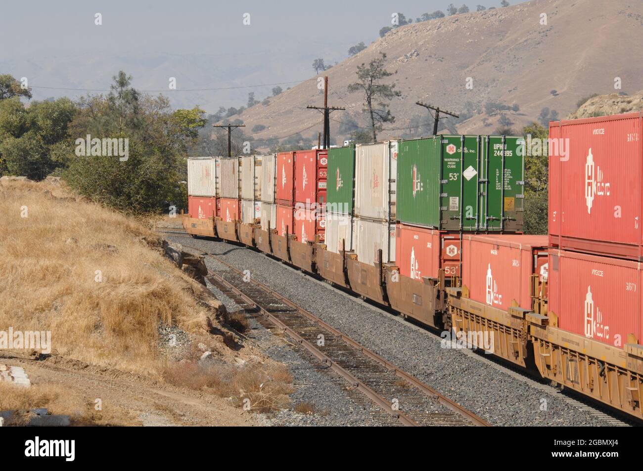 Shipping containers on well cars move past Keene, California Stock Photo