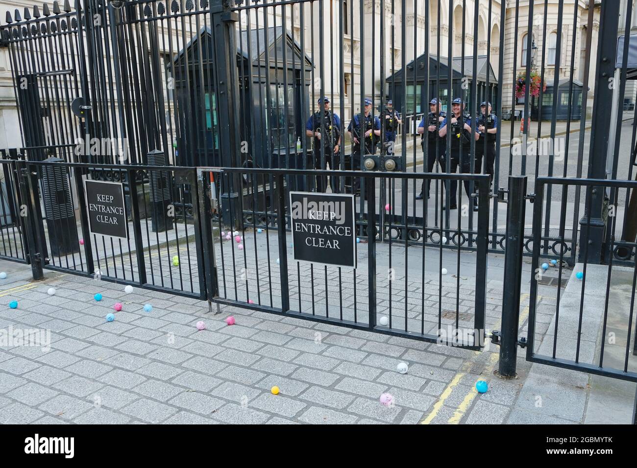 Protesters demonstrating against Covid-19 vaccinations for children pause by Downing Street where they throw colourful balls containing messages. Stock Photo