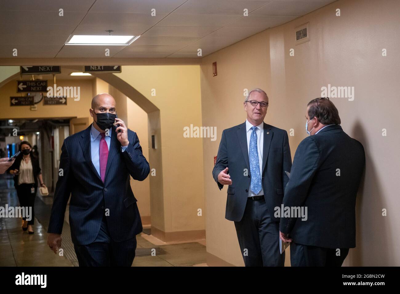 Washington, Vereinigte Staaten. 04th Aug, 2021. United States Senator Cory Booker (Democrat of New Jersey), left, walks past while United States Senator Kevin Cramer (Republican of North Dakota) talks with a reporter in the Senate subway during a vote on amendments to H.R. 3684, the Infrastructure Investment and Jobs Act, at the US Capitol in Washington, DC, Wednesday, August 4, 2021. Credit: Rod Lamkey/CNP/dpa/Alamy Live News Stock Photo