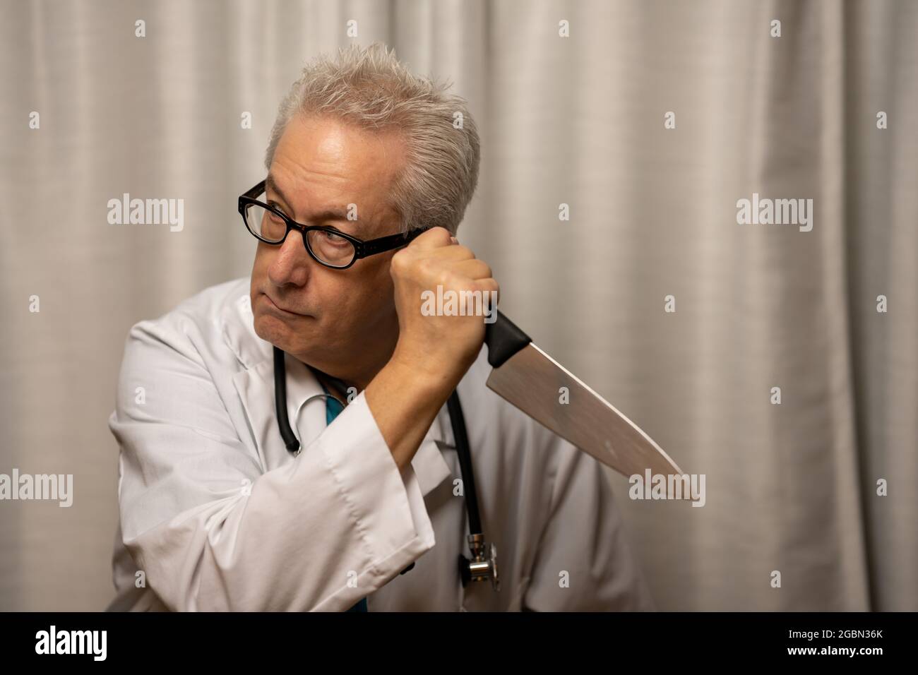 Evil medical doctor holding knife in hand to murder his patients Stock Photo