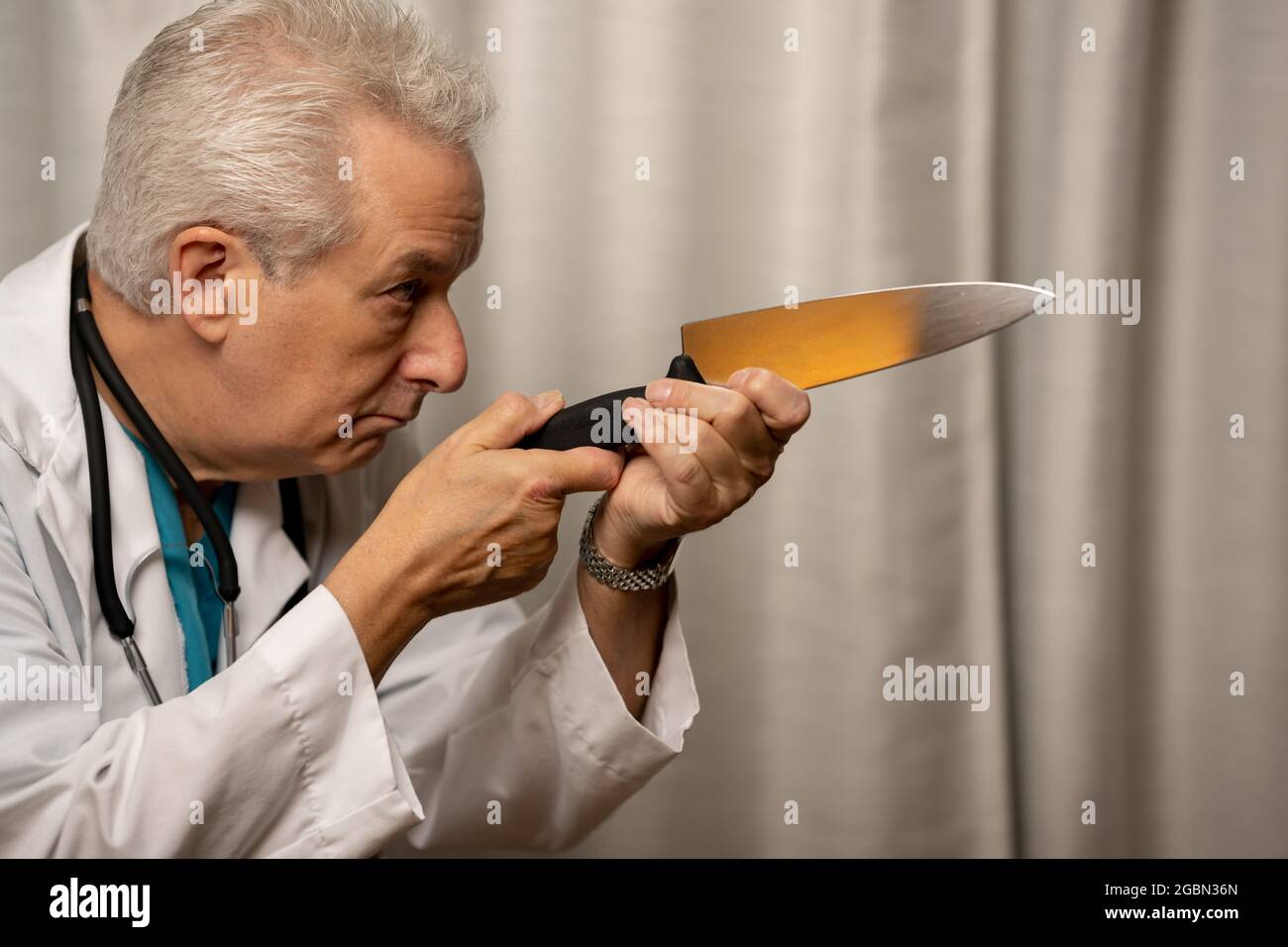 Evil medical doctor holding knife in hand to murder his patients Stock Photo