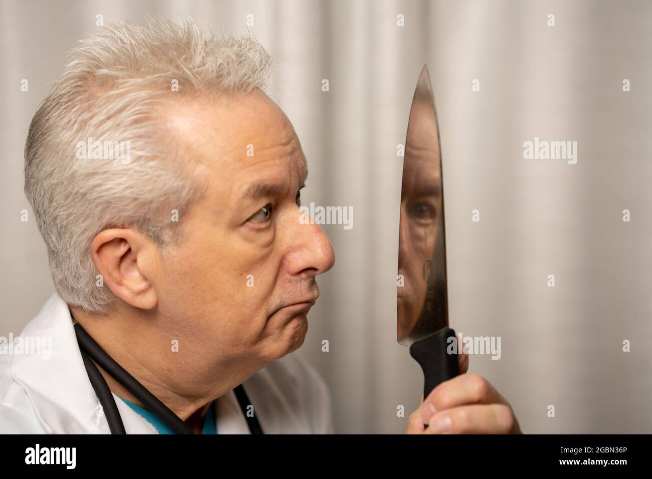 Evil medical doctor holding knife in hand to murder his patients Stock Photo