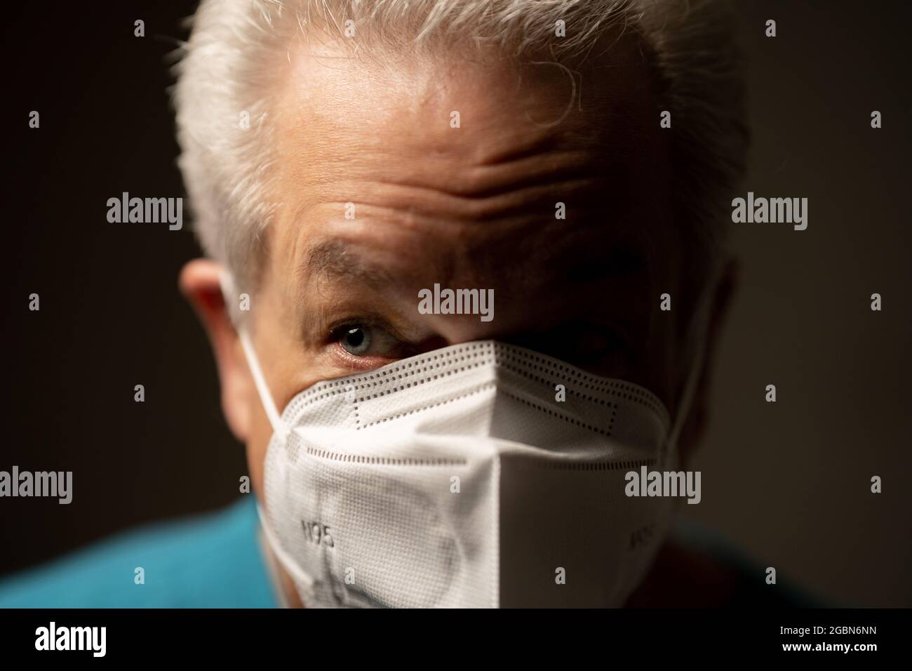 Side light photo of an old man wearing a face mask Stock Photo