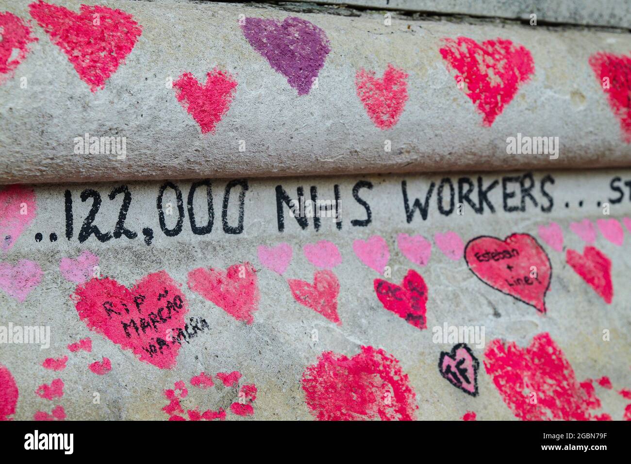 The words '122,000 NHS Workers..' inscribed amidst the thousands of hearts on the Covid19 memorial wall.  The National Covid Memorial Wall runs for about a mile along the Thames river alongside St Thomas' hospital in Westminster. The memorial began around April 2021 and its decorated with more than 150,000 red hearts each representing a life lost to Covid19. (Photo by David Mbiyu / SOPA Images/Sipa USA) Stock Photo