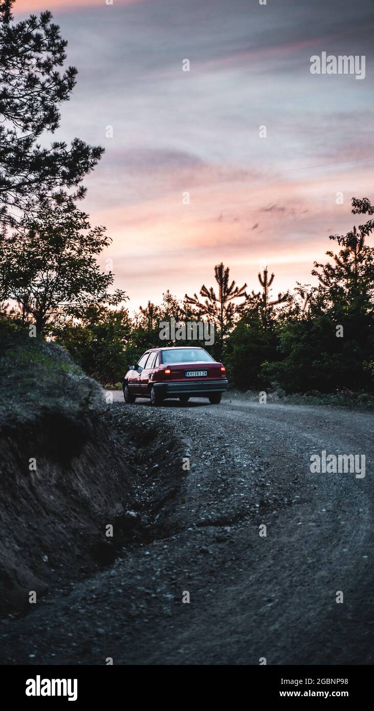 Vertical shot of a car driving through a winding road at sunset Stock ...