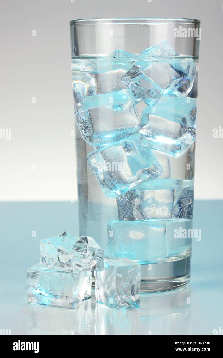 Ice cubes in glass on light blue background Stock Photo - Alamy