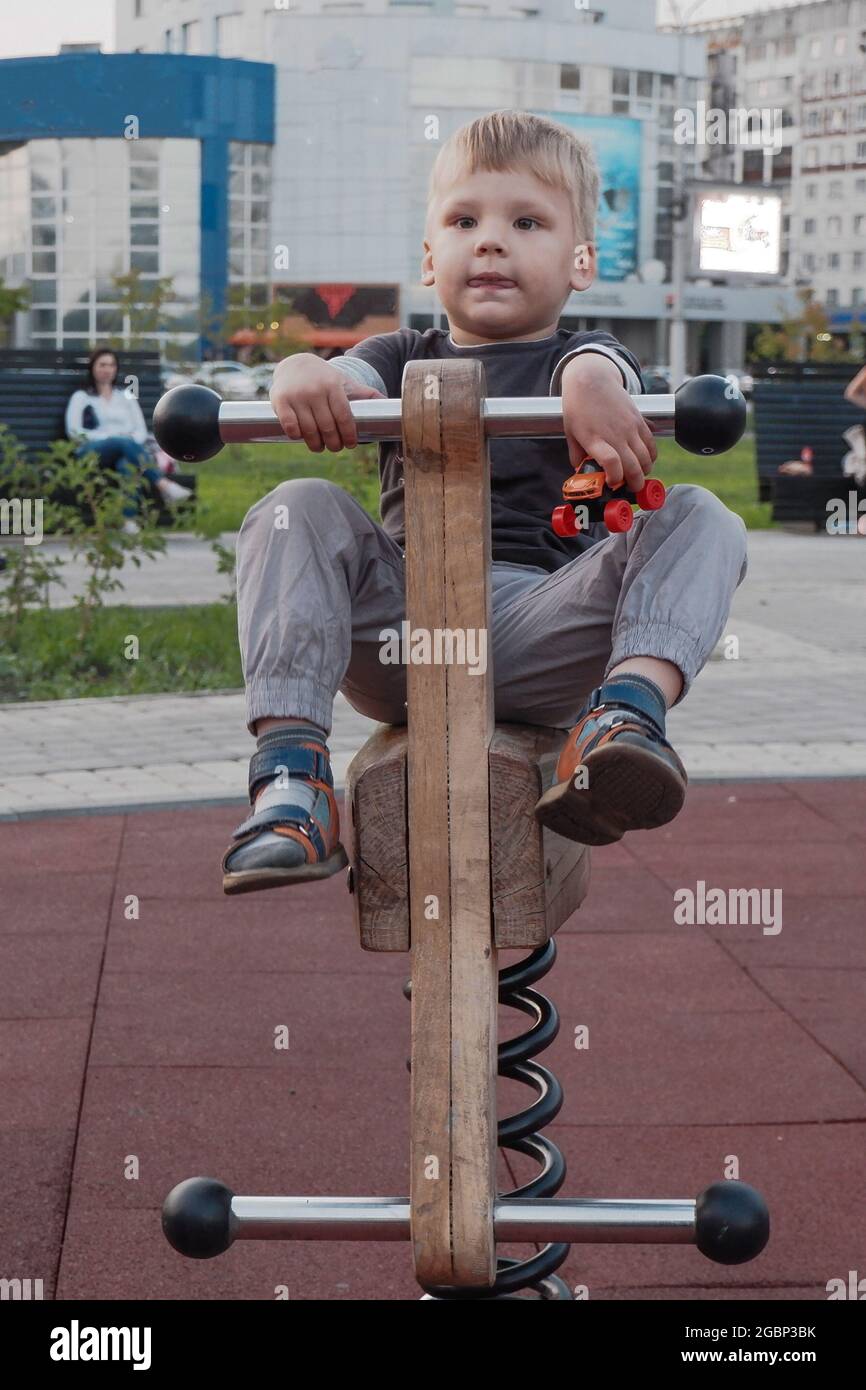 a little boy plays on a children's attraction at a children's city playground. Stock Photo