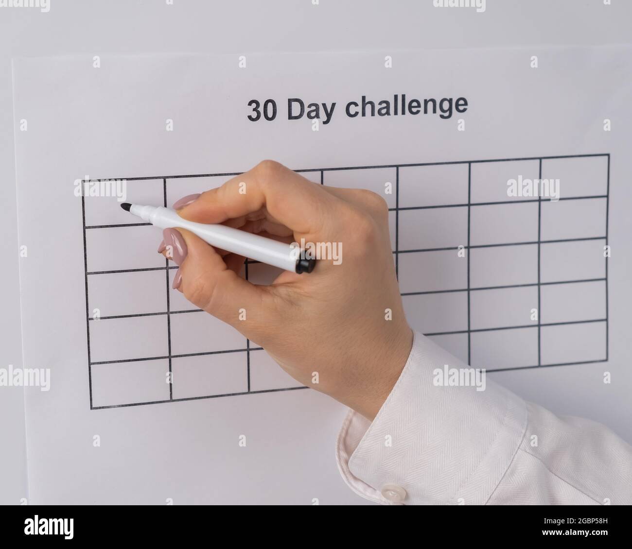 Cropped view of woman writing check marks in boxes of 30 days challenge ...