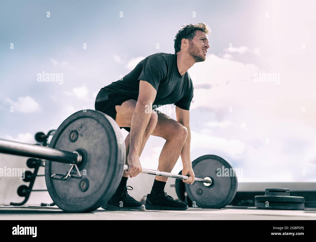 Gym fitness weightlifting deadlift man bodybuilding powerlifting at outdoor summer health club. Bodybuilder doing barbell weight lifting training Stock Photo