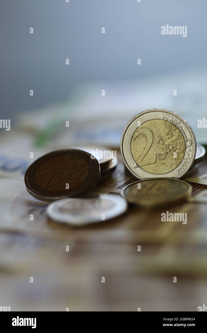 Two euro coins and euro banknotes on a blurred green background.Money. European currency. Finance and savings.  Stock Photo