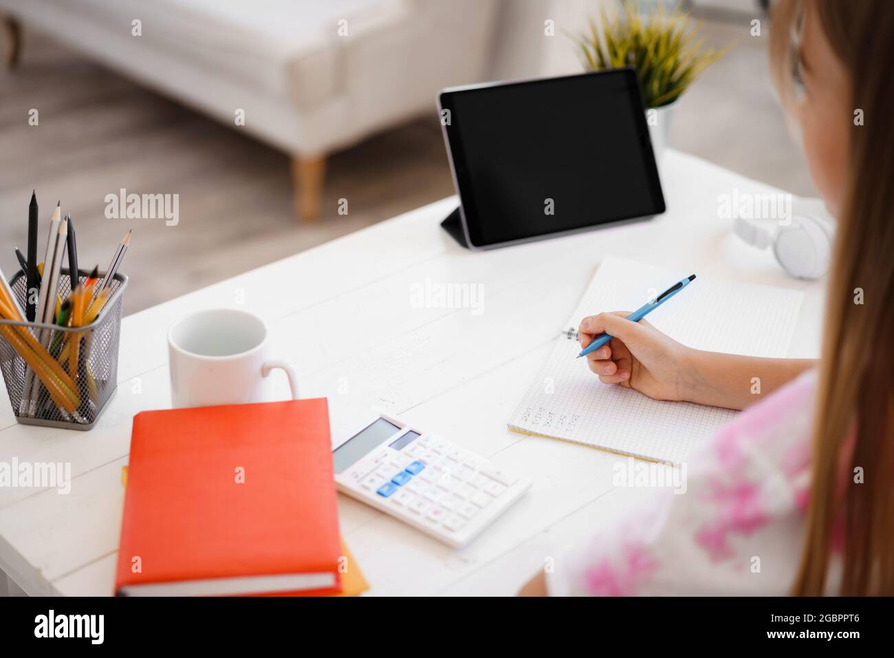 Teenage girl making notes in notepad, doing homework at table at home ...