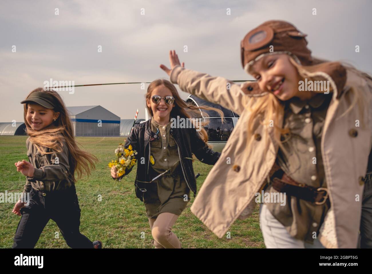 Cheerful tween girls running on flying field of aeroclub Stock Photo