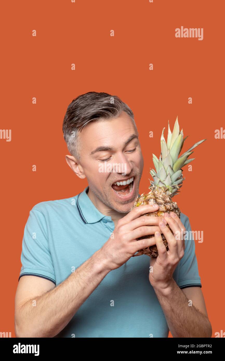 Man holding pineapple near open mouth Stock Photo Alamy