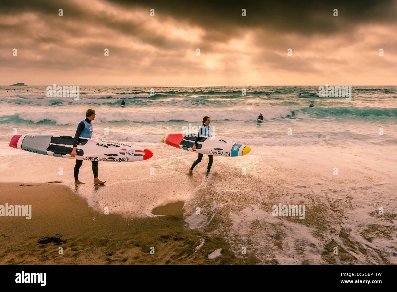 Late evening light over members of Newquay Surf Lifesaving Club at a training session on Fistral Beach in Newquay in Cornwall. Stock Photo