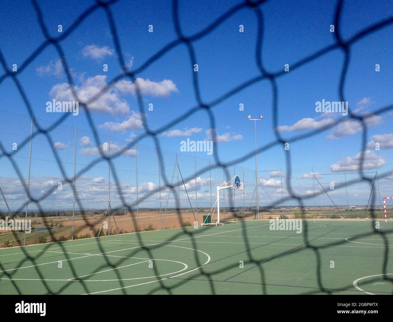 Urban multisports court seen behind safety net. Blue cloudy sky Stock Photo
