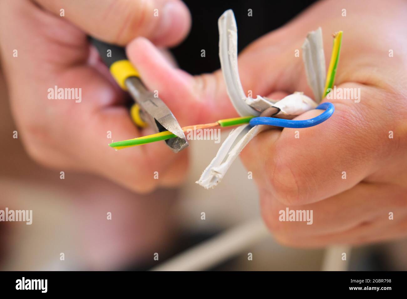 Young man hands peeling a wire using a plier to repair it. Stock Photo