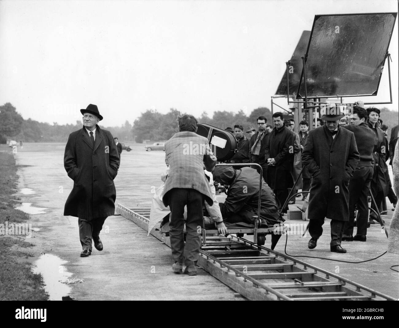SPENCER TRACY as Chief Judge Dan Haywood walks around the old Nuremberg Nazi Rally Site on set location candid with Director STANLEY KRAMER  (walking with hat and overcoat) and Movie Crew during filming of JUDGEMENT AT NUREMBERG 1961 director STANLEY KRAMER based on original story by Abby Mann cinematography Ernest Laszlo music Ernest Gold Roxlom Films Inc. / United Artists Stock Photo