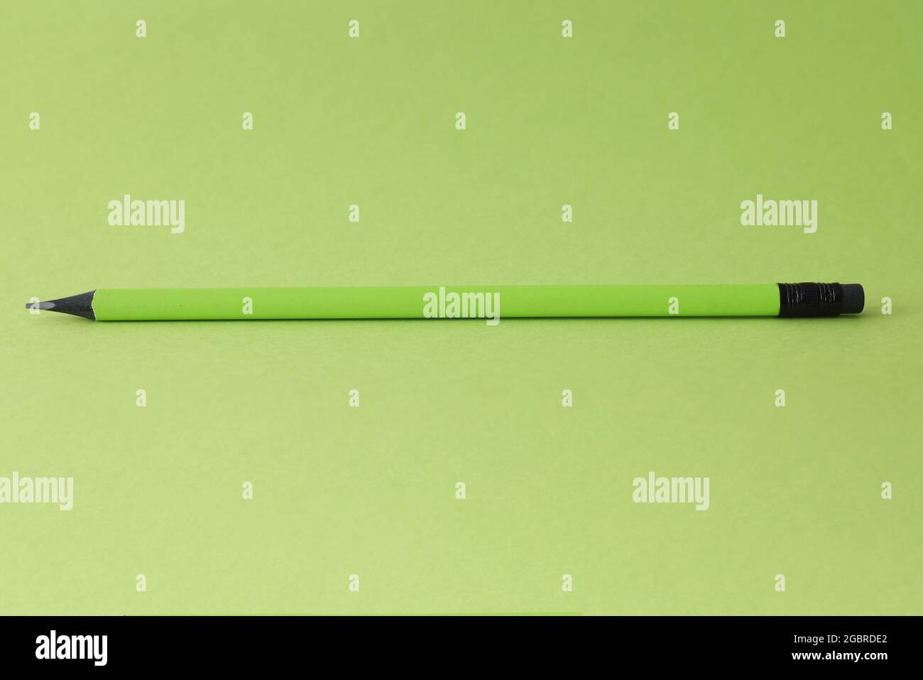 Sharp simple pencil lying on green background closeup Stock Photo