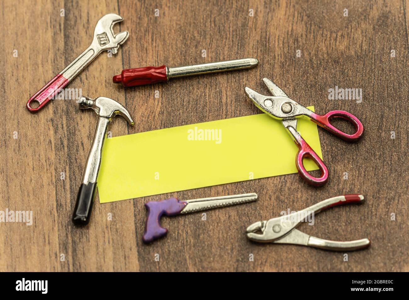 Crafting concept: A sticky note surrounded by miniature crafting tools. Text space. Stock Photo