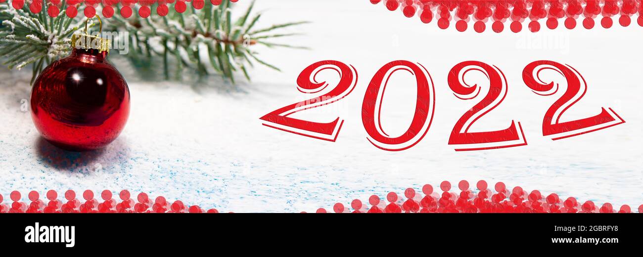 Holiday card New Year 2022 banner. A red Christmas ball and a snow-covered tree branch on a snowy white background. Stock Photo