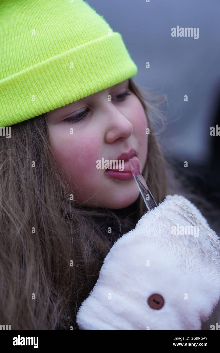 Little girl with long hair licking frozen icicle. Selective focus. Stock Photo