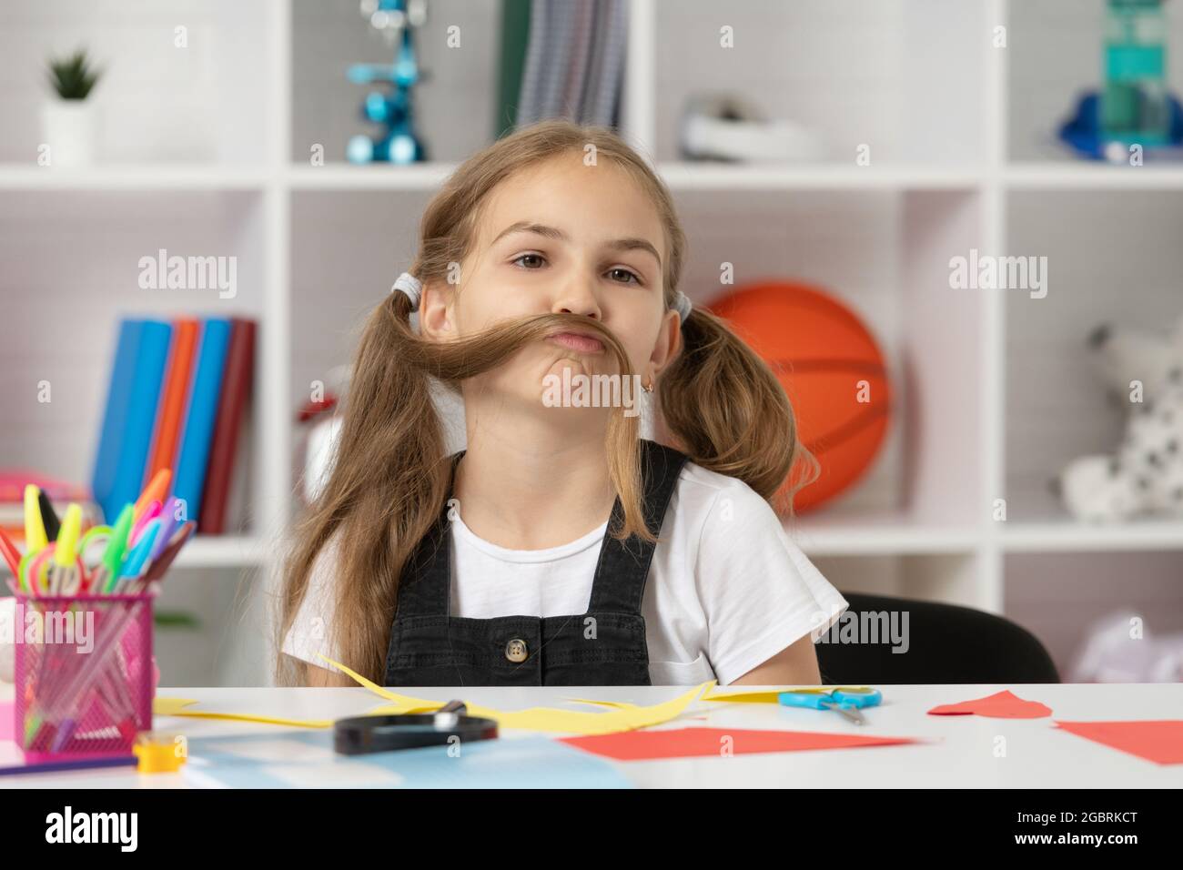 funny child having fun with long hair pony tail at school lesson in classroom wear uniform, fun Stock Photo