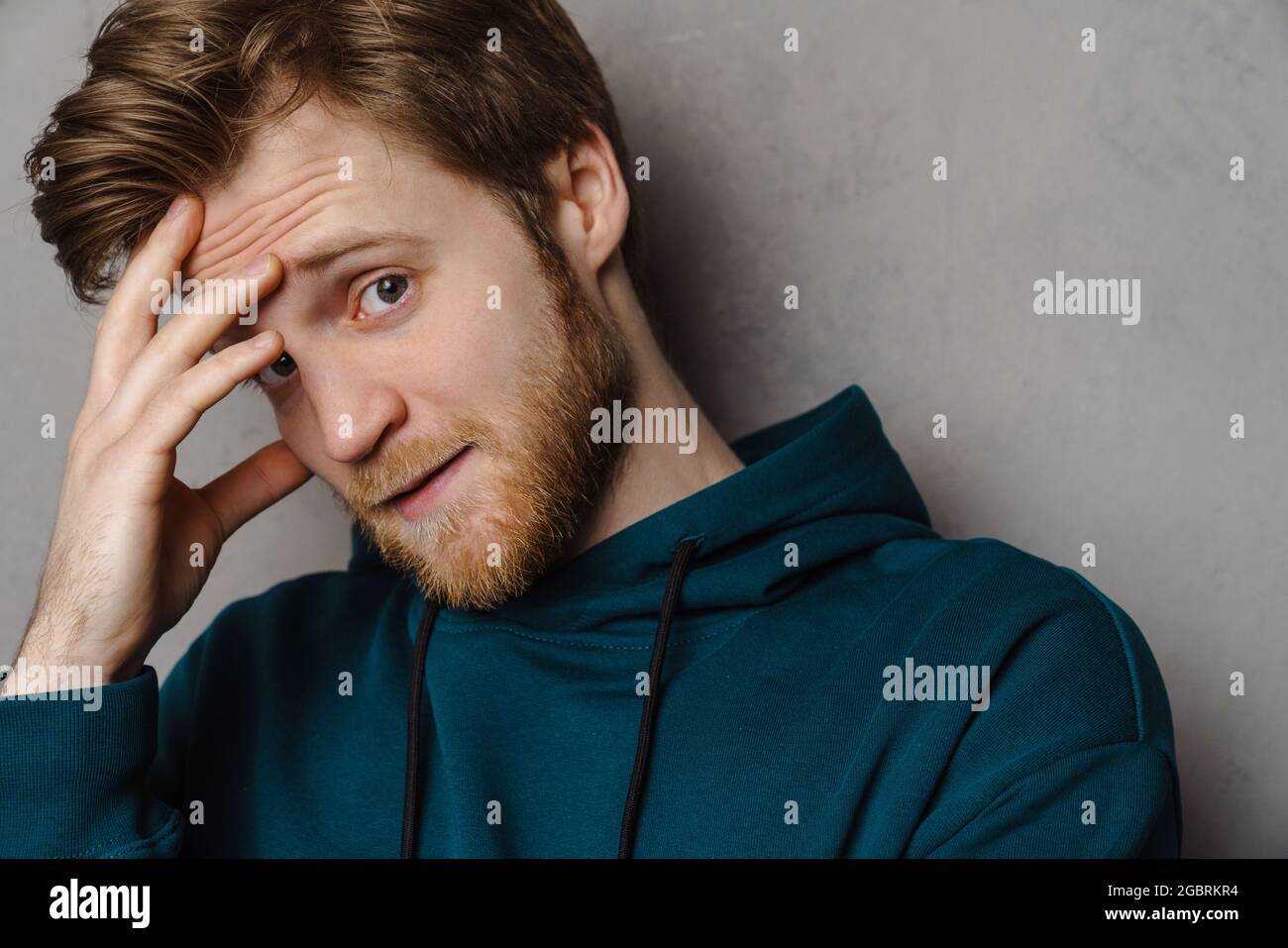 White ginger man with beard posing and covering his face isolated over grey background Stock Photo