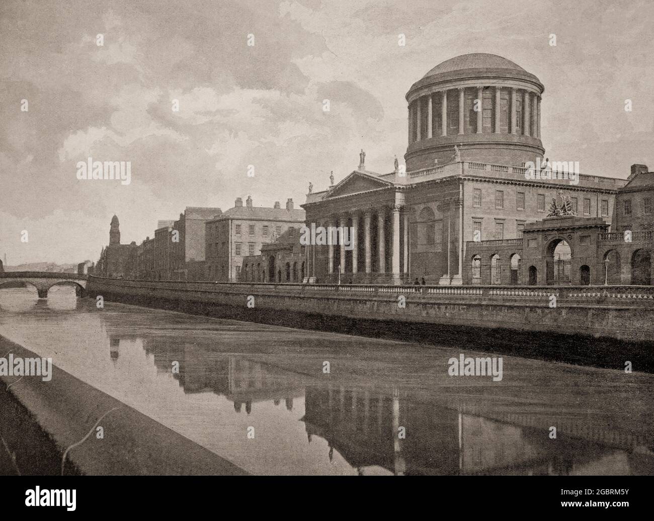 A late 19th century view of the Four Courts reflected in the River Liffey. The building is Ireland's most prominent courts building, located on Inns Quay in Dublin and the principal seat of the Supreme Court, the Court of Appeal, the High Court and the Dublin Circuit Court. It was based on the design of Thomas Cooley for the Public Records Office of Ireland, but after his death in 1784, the renowned architect James Gandon was appointed to finish the building. Built between 1786 and 1796, the finishing touches to the arcades and wings were completed in 1802. Stock Photo