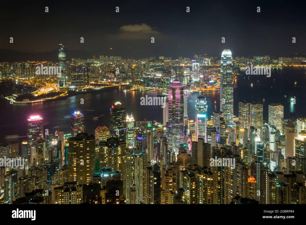 The skyscrapers and high density highrise urban landscape of Mid-levels and Central on Hong Kong Island, and Kowloon across Victoria Harbour, at night Stock Photo