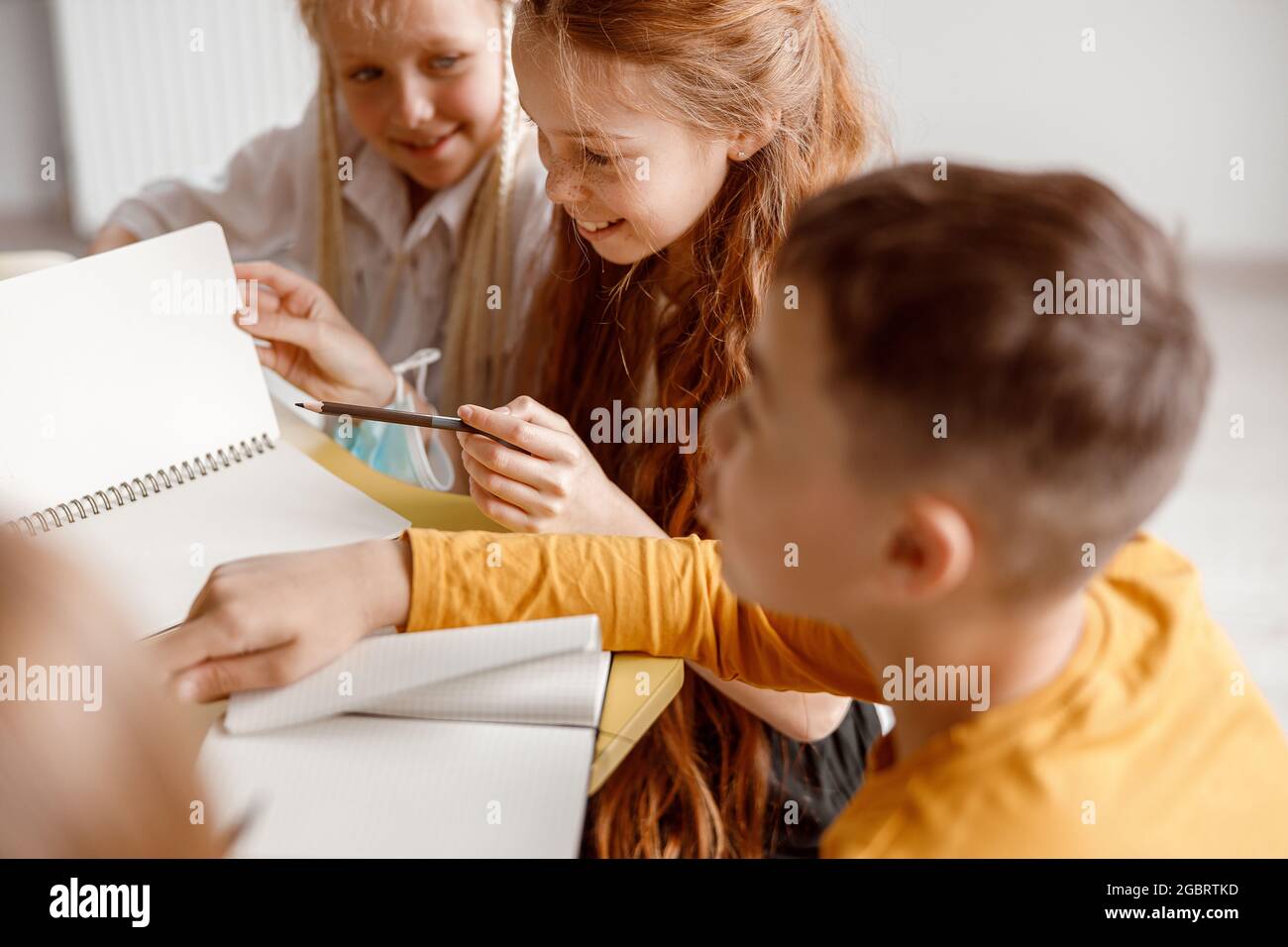 Happy children sitting at the table and using notebooks Stock Photo