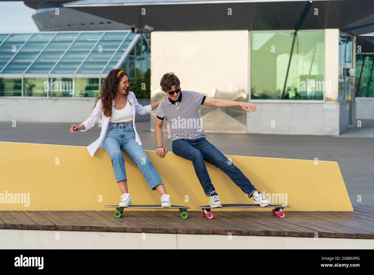Carefree hipster man and woman young couple having fun after skateboarding laugh enjoy time together Stock Photo
