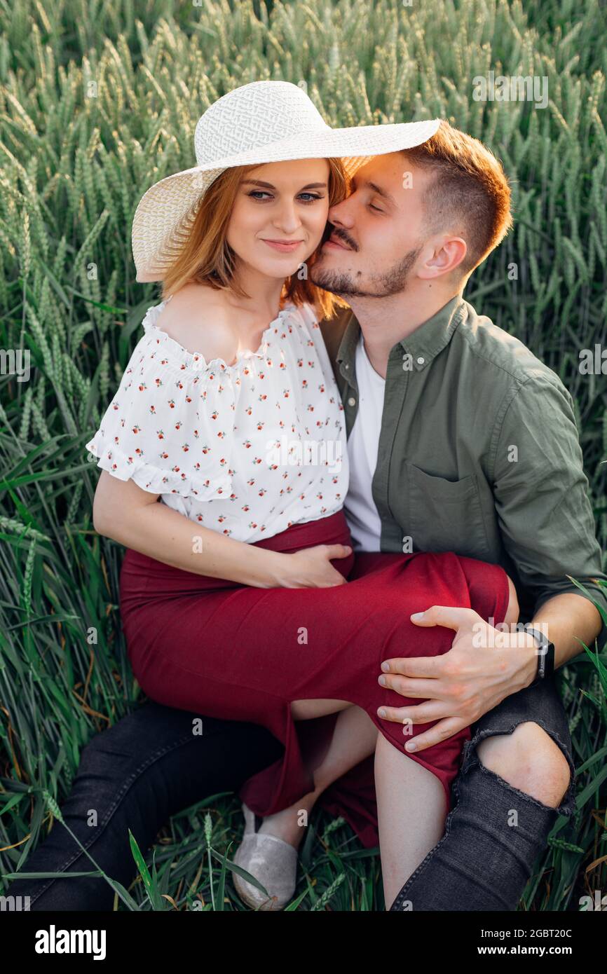 Young man hugs and kisses his beautiful pregnant wife sitting on his