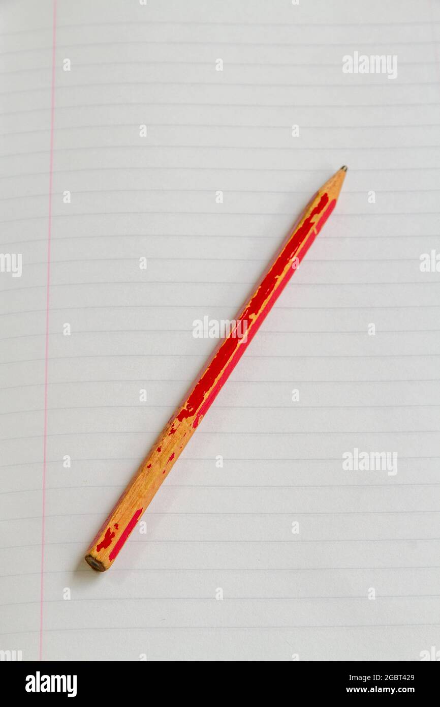 Overhead view of a pencil lying on a blank page of a notebook. Vertical format, space for copy Stock Photo