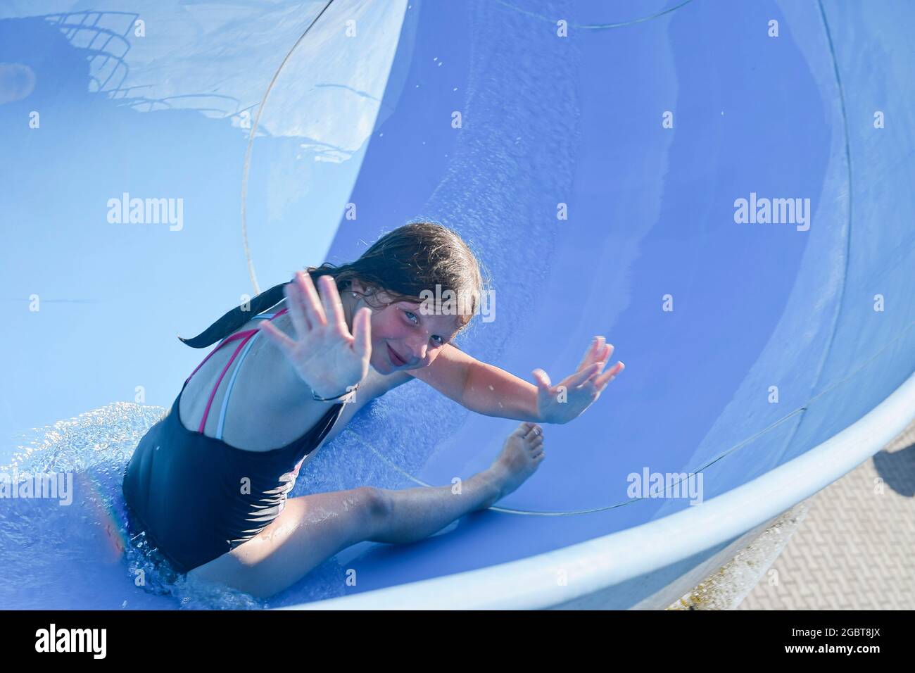 Pretty little girl sliding on water slide. Funny children's attraction