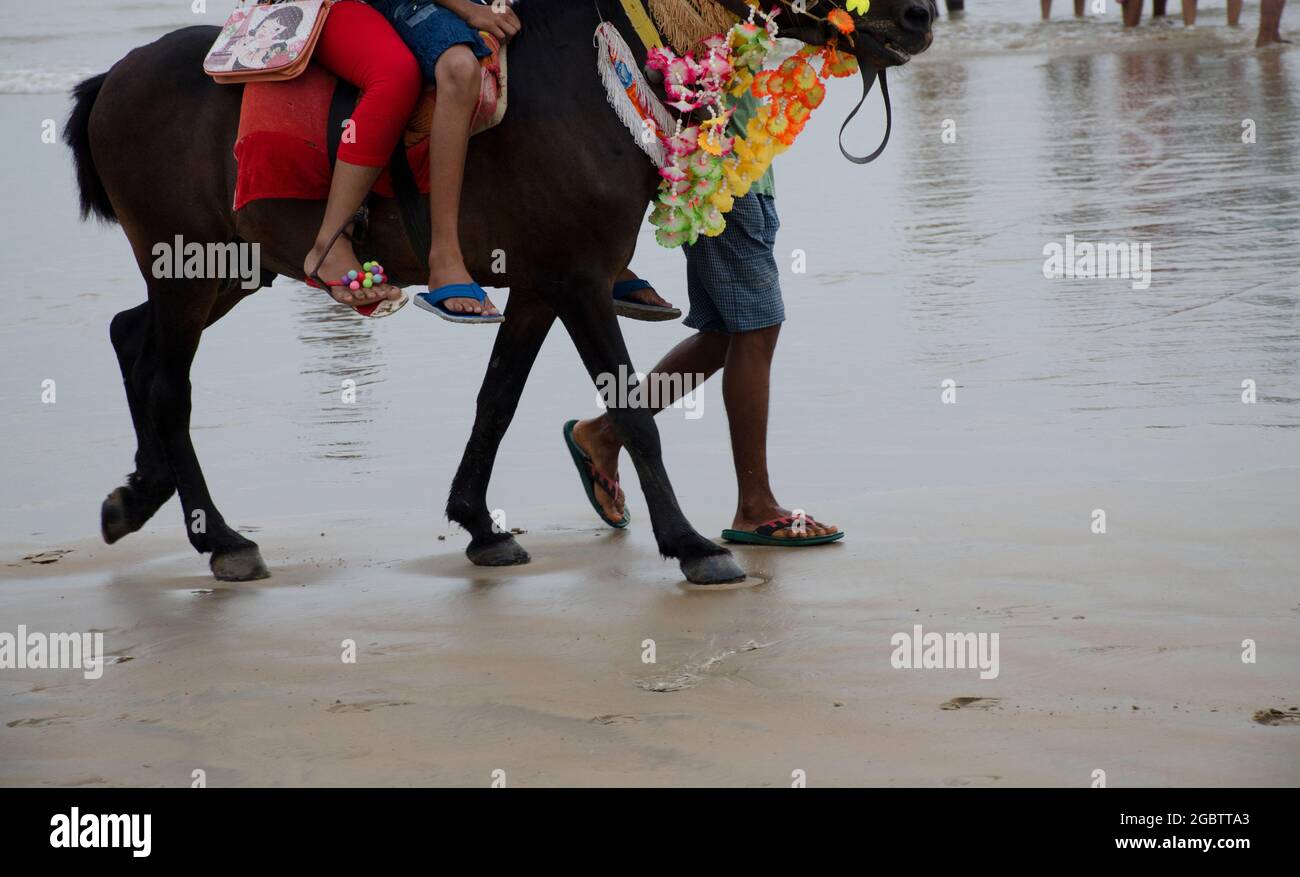 Children are riding on horse back along the sea shore of Digha, India. Stock Photo