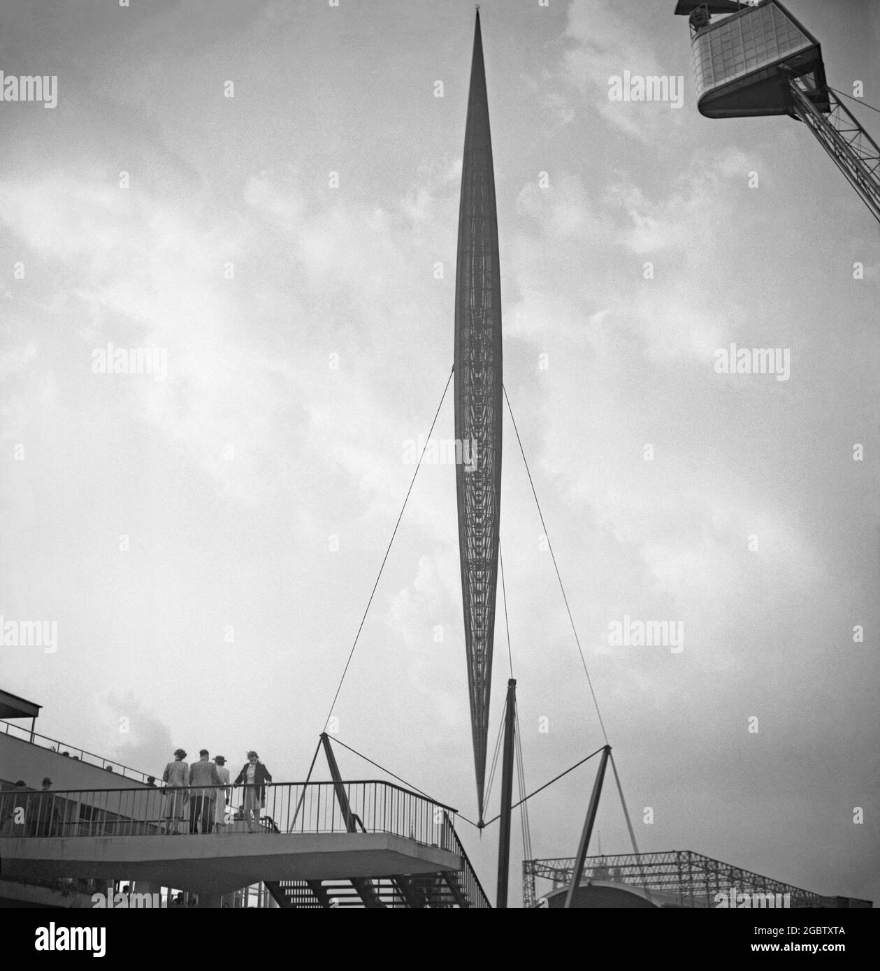 A view of the Skylon at the Festival of Britain’s South Bank Exhibition, London, England, UK in 1951. The Skylon was a futuristic, slender steel structure. It gave the illusion of 'floating' above the ground and became a symbol of the festival. It was designed by Hidalgo Moya, Philip Powell and Felix Samuely and was fabricated by Painter Brothers of Hereford, England. The Skylon consisted of a steel latticework frame and supported by cables and steel beams. The frame was clad in aluminium louvres lit from within at night. The Skylon was removed in 1952 when the site was cleared. Stock Photo
