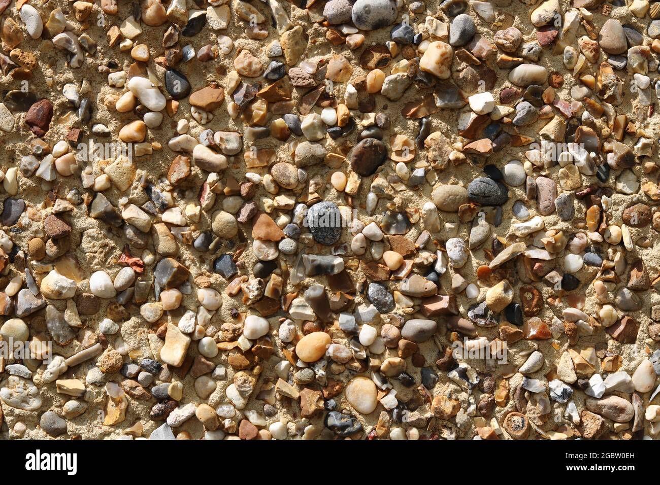 Textured pebbledash background with stones in a variety of colours Stock Photo