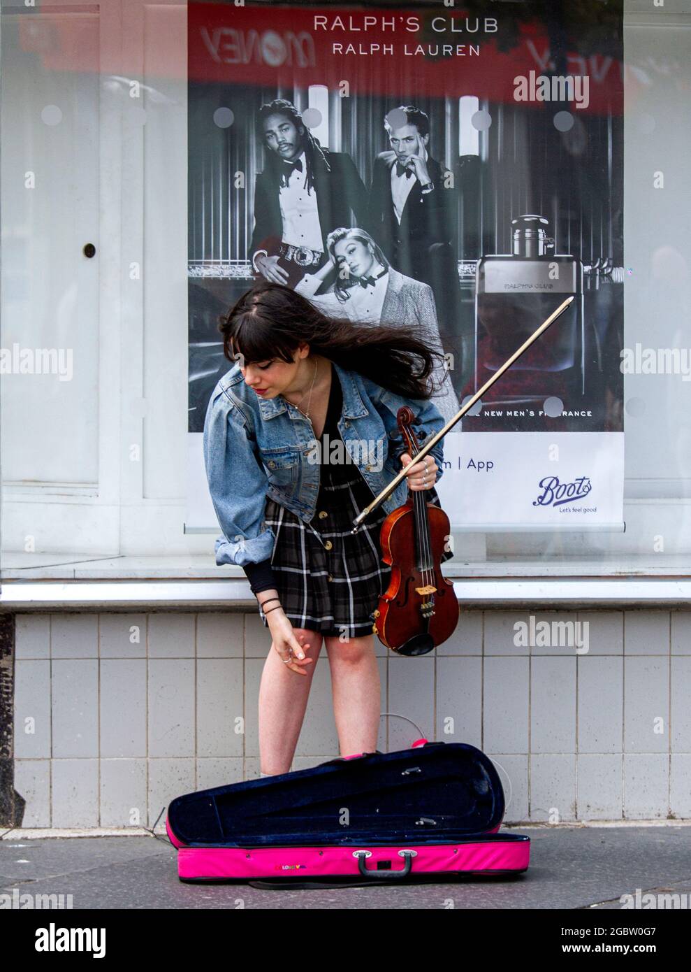 Dundee, Tayside, Scotland, UK. 5th Aug, 2021. UK Weather: A bright and windy day with sunny spells across North East Scotland with temperatures reaching 20°C. A young female violinist playing classical music whilst busking in the wind outside Boots the Chemist in Dundee city centre. Credit: Dundee Photographics/Alamy Live News Stock Photo