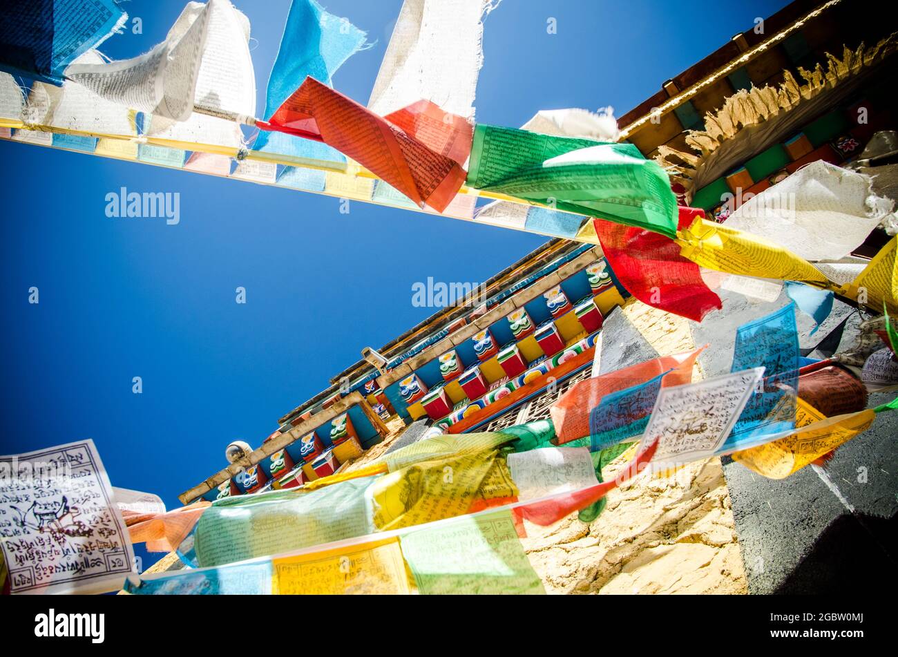 Colorful Tibetan prayer flags spreading good fortune and blessings hanging on the wall of the monastery. Stock Photo