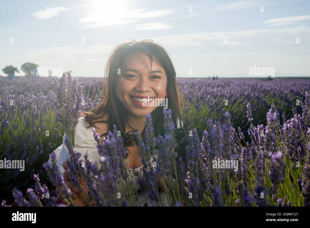 outdoors romantic portrait of young happy and attractive woman in white summer dress enjoying carefree at beautiful lavender flowers field in travel a Stock Photo