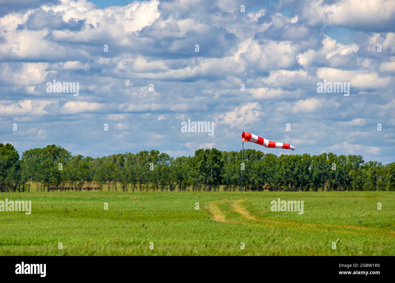 a windsock in the form of a red and white fabric cone is fully deployed on the airfield of the airfield Stock Photo