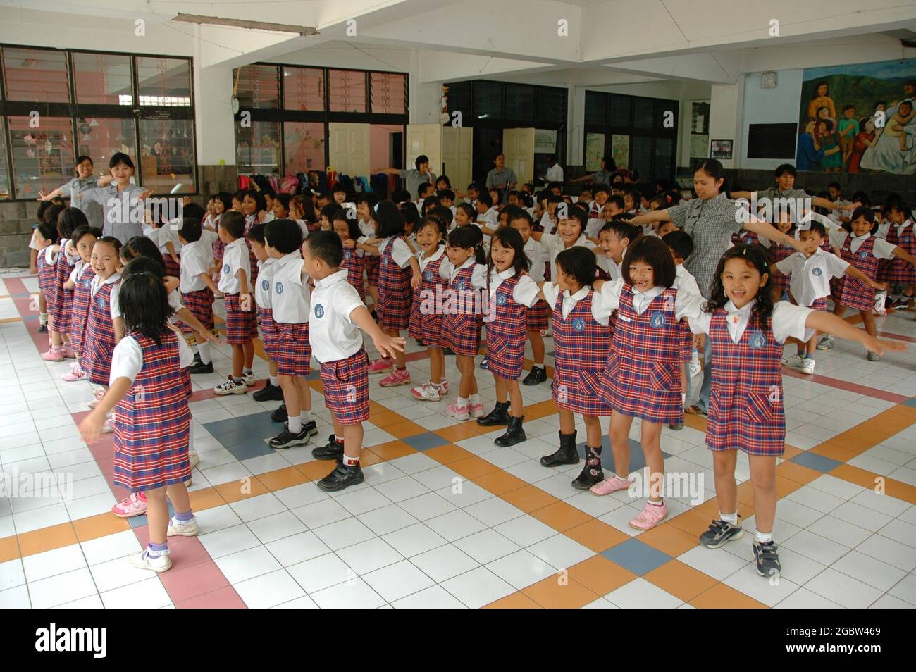 A group of kindergarten students line up in a hall with their teachers. Stock Photo