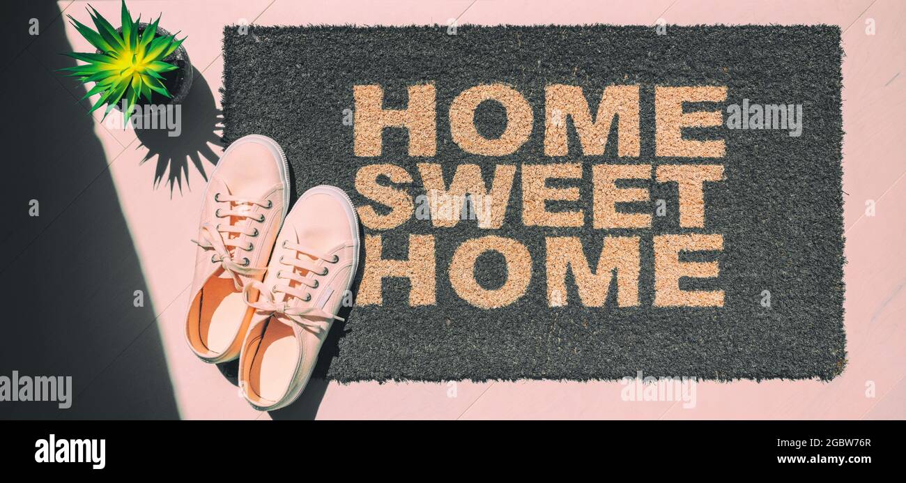 Home sweet home doormat. Homeowner moving in new house concept with top view of pink shoes and entrance door mat. Panoramic banner background Stock Photo