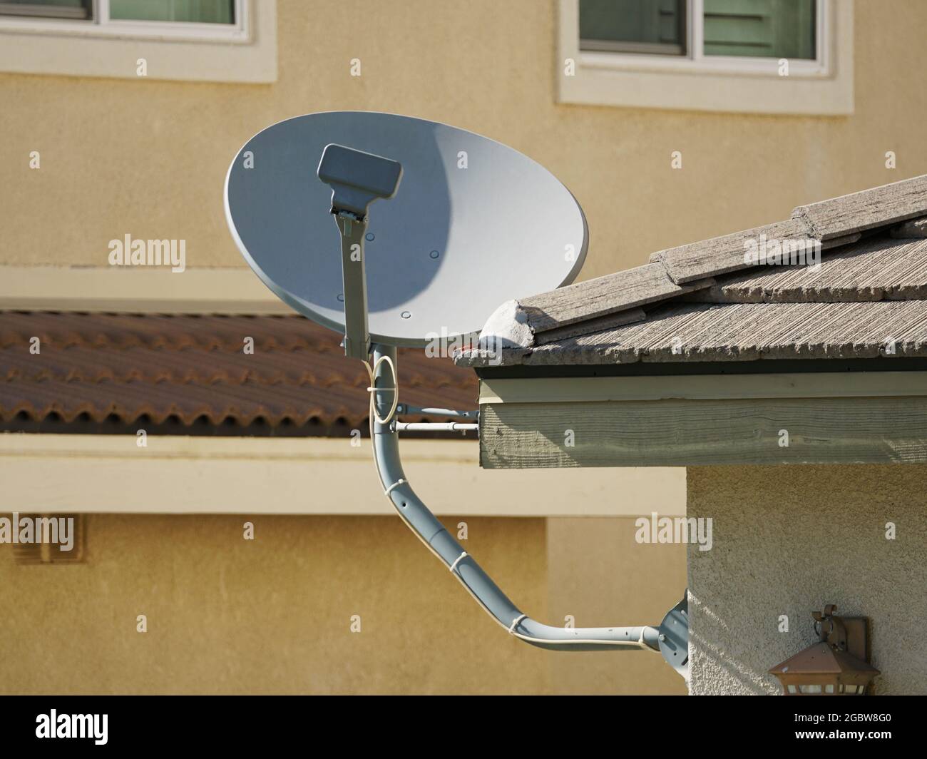 Residential satellite TV dish installed on eave of house Stock Photo