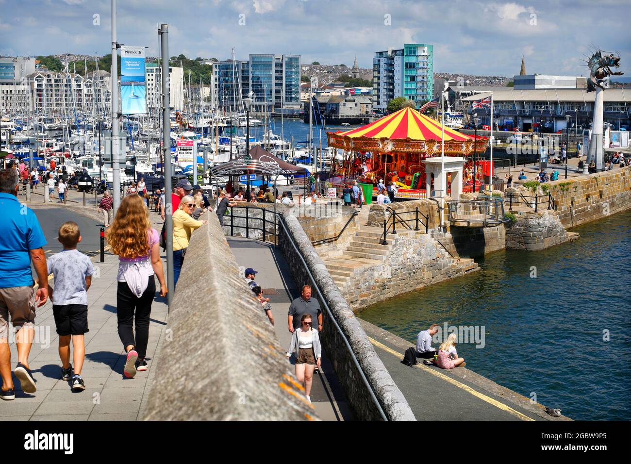 The Barbican in Plymouth, Devon, UK. View looking towards Sutton Harbour with the Mayflower Steps seen in front of the Victorian Carousel. Stock Photo
