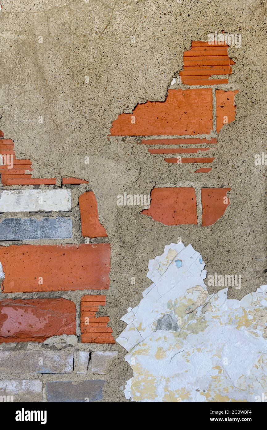 Decayed red brick wall with peeling paint forms abstract background Stock Photo