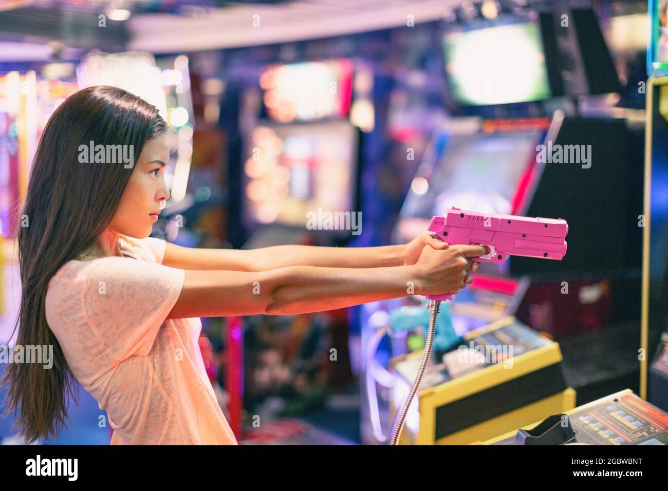 Arcade game machine adult woman shooting gun video games playing light shoot videogame virtual reality Stock Photo
