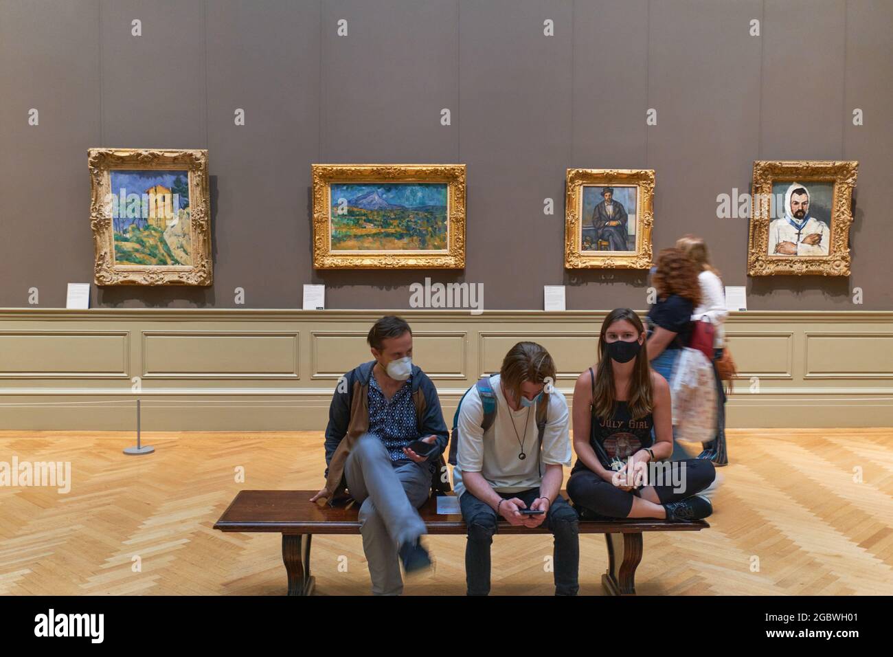 People sitting in the Metropolitan Museum Of Art with Paul Cezanne paintings behind Stock Photo