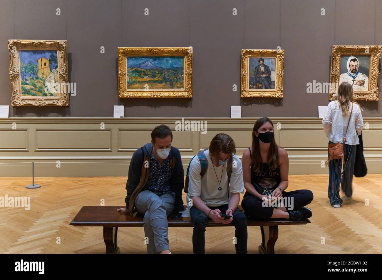 People sitting in the Metropolitan Museum Of Art with Paul Cezanne paintings behind Stock Photo
